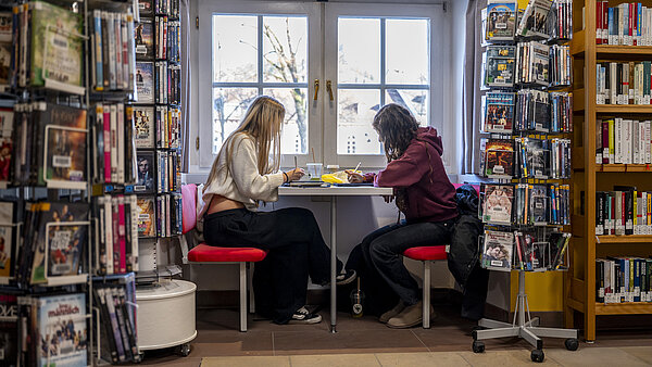 Zwei Jugendliche sitzen an einem Tisch und lernen