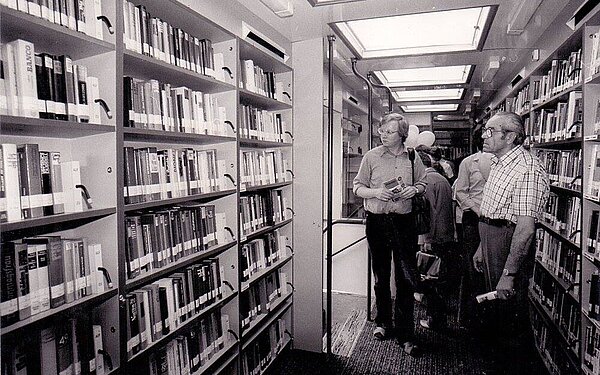 Die dritte Generation von innen. Ein schwarz-weiß Bild. Man sieht volle Regale und Menschen im Bus