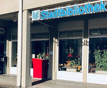 Der Eingang der Stadtteilbibliothek Waldstadt von vorne mit rotem Medienrückgabekasten.