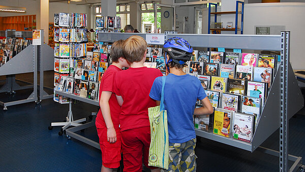 Drei Jungs stehen vor den CDs und DVDs