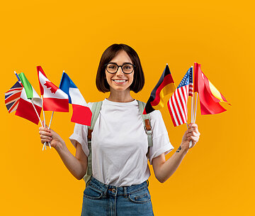 Frau lächelt und hält verschiedene Länderflaggen hoch