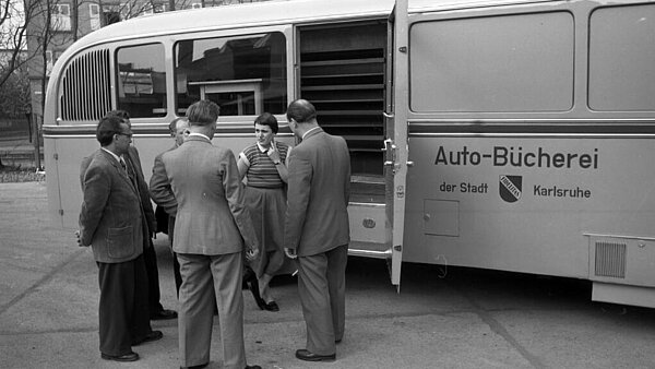 Die erste Generation hieß "Autobücherei". Auf dem schwarz-weiß Foto stehen Menschen vor der Autobücherei, deren Tür geöffnet ist