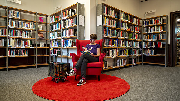 Frau liest in rotem Sessel