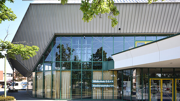 Außenansicht der Badnerlandhalle mit der Beschriftung "Bibliothek" an der Fassade, die zum Bibliothekseingang auf der Rückseite der Halle weist.