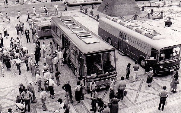 Die zweite und dritte Generation stehen auf dem Karlsruher Marktplatz nebeneinander bei der Pyramide. Das Bild ist schwarz-weiß und von oben aufgenommen. Um die Busse stehen viele Menschen