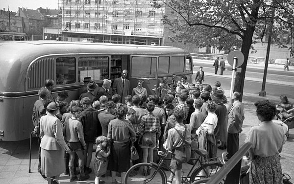 Eine große Menschentraube steht vor der Autobücherei, ein schwarz-weiß Foto