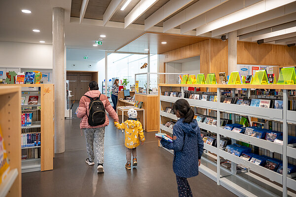Frau mit Kindern geht durch Stadtbibliothek Mühlburg