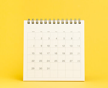 Ein weißer Aufstell-Tischkalender vor gelbem Hintergrund