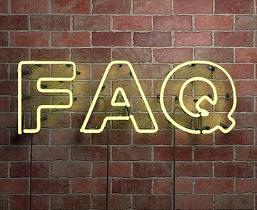 Die Neonleuchtbuchstaben F, A und Q vor an einer Backsteinmauer hängend