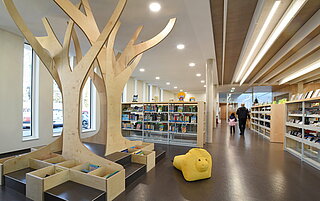 Die Stadtteilbibliothek Mühlburg von innen. Ein hell erleuchteter, moderner, großer Raum mit vielen Bücherregalen.
