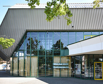 Außenansicht der Badnerlandhalle mit der Beschriftung "Bibliothek" an der Fassade, die zum Bibliothekseingang auf der Rückseite der Halle weist.