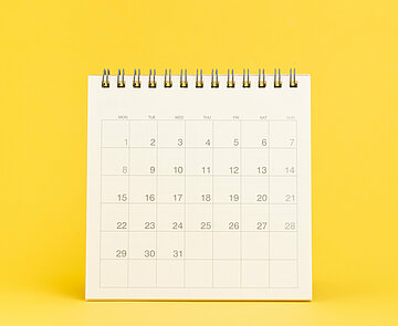 Ein weißer Aufstell-Tischkalender vor gelbem Hintergrund