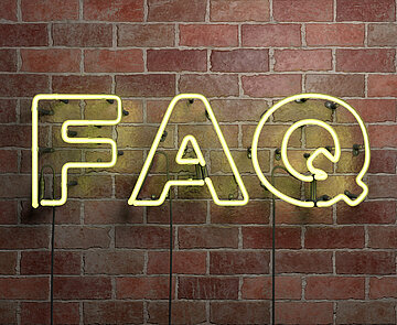 Die Neonleuchtbuchstaben F, A und Q vor an einer Backsteinmauer hängend